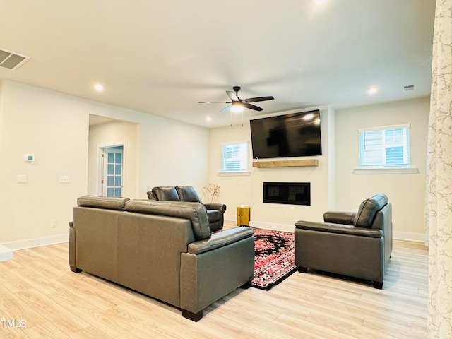 living room with a wealth of natural light, ceiling fan, and light wood-type flooring