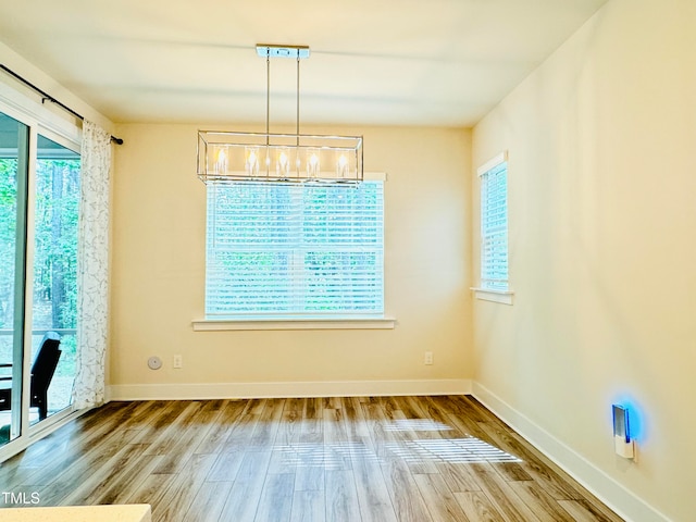 unfurnished dining area with wood-type flooring and a chandelier