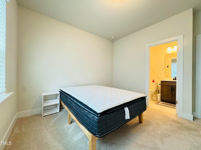 carpeted bedroom with ensuite bathroom and multiple windows