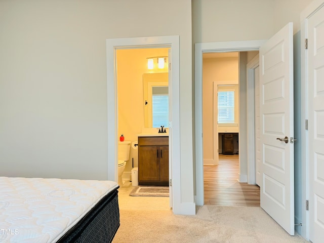 carpeted bedroom featuring ensuite bathroom and sink