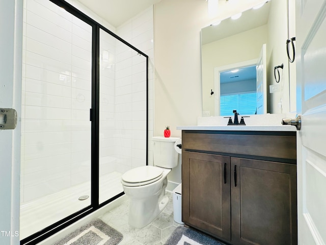 bathroom with a shower with door, vanity, tile patterned floors, and toilet