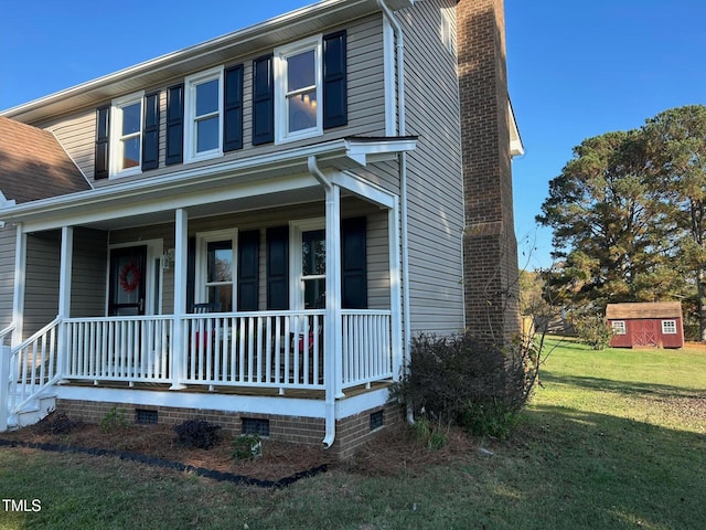 view of front of home with covered porch, a front lawn, and a storage shed