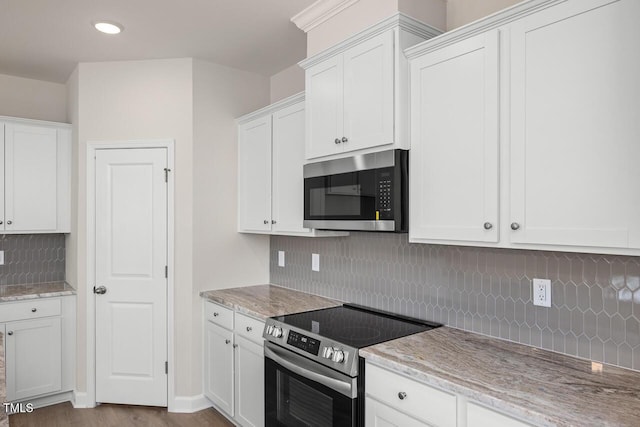 kitchen with white cabinets, hardwood / wood-style floors, appliances with stainless steel finishes, and tasteful backsplash