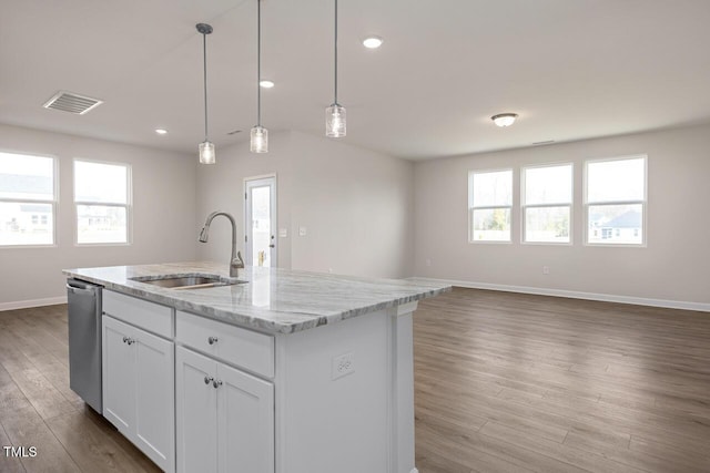 kitchen with light stone countertops, dishwasher, white cabinetry, sink, and a center island with sink