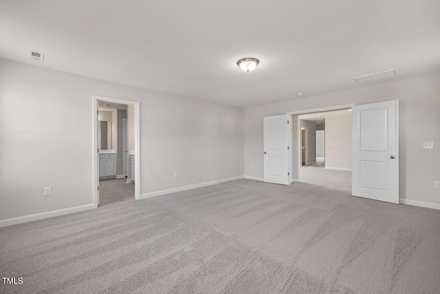 unfurnished bedroom featuring connected bathroom and light carpet