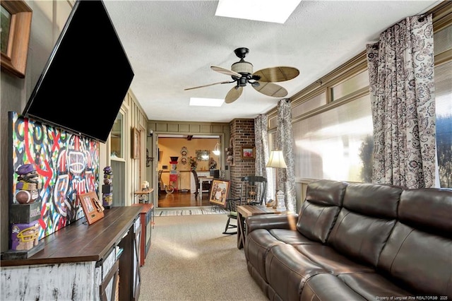 carpeted living room with ceiling fan, a textured ceiling, and a skylight