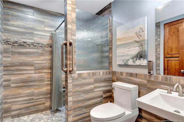 bathroom featuring toilet, curtained shower, sink, and tile walls