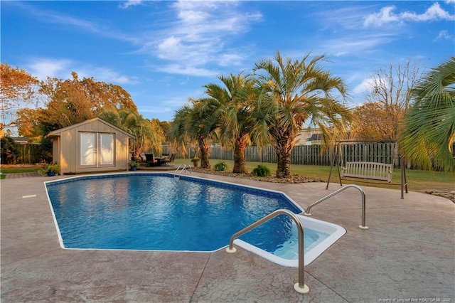 view of swimming pool featuring a patio area and a storage shed