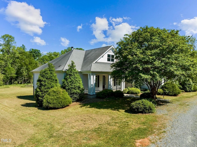 view of side of home featuring a lawn and covered porch