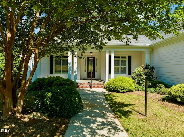 doorway to property with a yard and covered porch