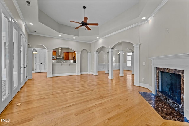 unfurnished living room featuring a fireplace, a raised ceiling, ornamental molding, and light hardwood / wood-style flooring