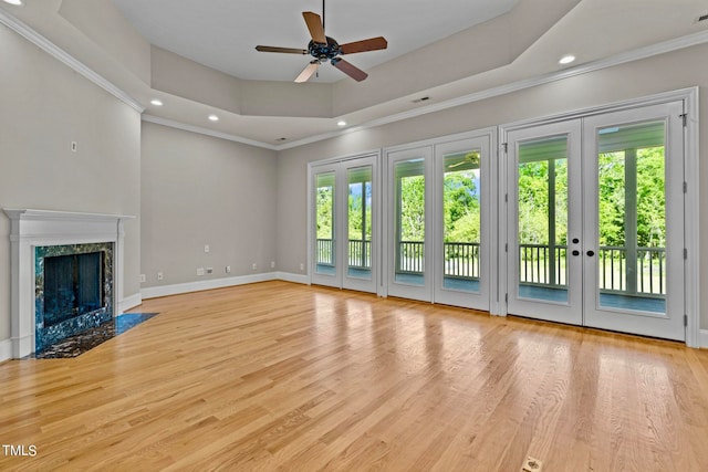 unfurnished living room with ornamental molding, light hardwood / wood-style floors, a healthy amount of sunlight, and a high end fireplace