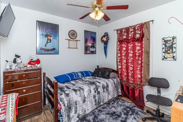 bedroom with ceiling fan, hardwood / wood-style floors, and a textured ceiling