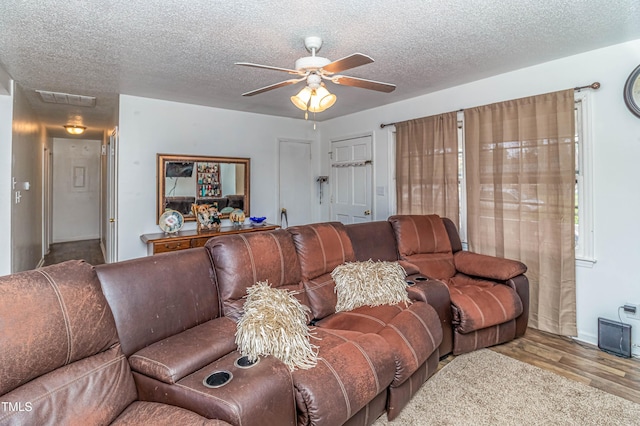 living room featuring ceiling fan, light hardwood / wood-style floors, and a textured ceiling