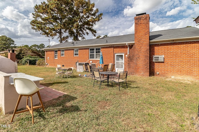 rear view of property featuring an AC wall unit, a patio area, and a lawn