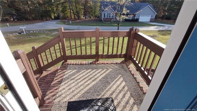 wooden terrace featuring a garage, a yard, and a porch