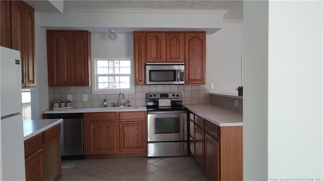 kitchen with stainless steel appliances, a textured ceiling, tasteful backsplash, sink, and light tile patterned flooring