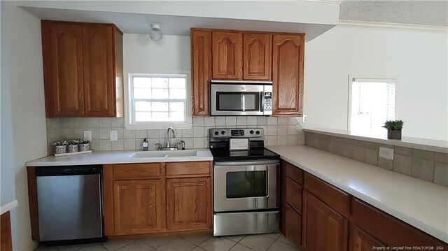 kitchen featuring appliances with stainless steel finishes, sink, tasteful backsplash, and light tile patterned floors