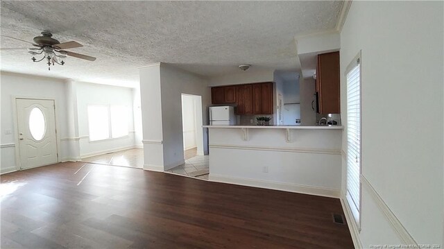 kitchen featuring white fridge, light hardwood / wood-style floors, a breakfast bar area, kitchen peninsula, and ceiling fan