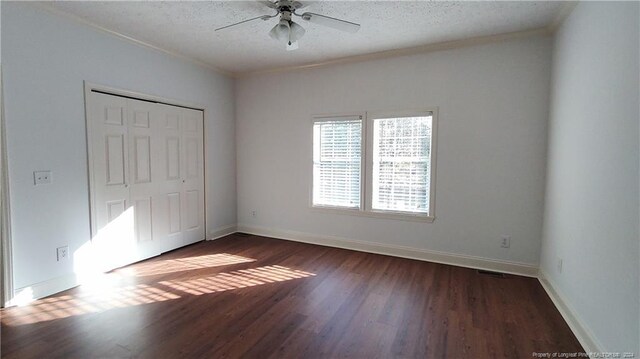 unfurnished bedroom featuring ornamental molding, ceiling fan, dark hardwood / wood-style floors, a textured ceiling, and a closet