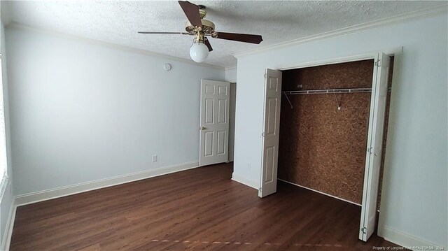 unfurnished bedroom with ceiling fan, a textured ceiling, crown molding, dark wood-type flooring, and a closet