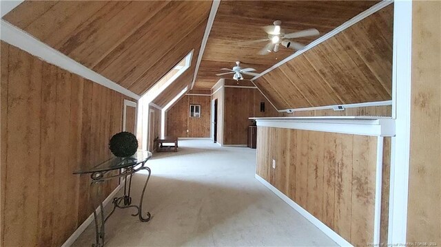 bonus room with vaulted ceiling with skylight, wooden walls, ceiling fan, and wooden ceiling