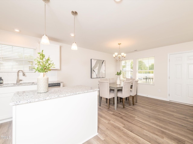 kitchen featuring white cabinetry, light hardwood / wood-style flooring, decorative light fixtures, and a kitchen island