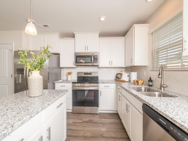 kitchen featuring white cabinetry, appliances with stainless steel finishes, dark hardwood / wood-style flooring, hanging light fixtures, and sink