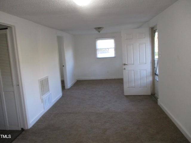 empty room with a textured ceiling and carpet flooring