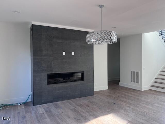 unfurnished living room featuring hardwood / wood-style flooring and a tile fireplace