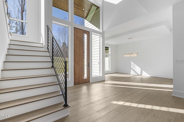 entrance foyer with a high ceiling, a healthy amount of sunlight, a chandelier, and light hardwood / wood-style flooring