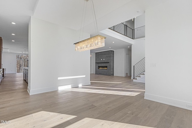 interior space with hardwood / wood-style flooring, a fireplace, an inviting chandelier, and a high ceiling