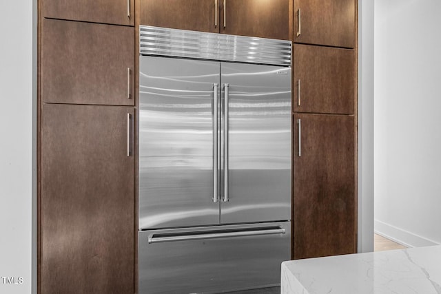 kitchen with built in refrigerator and light stone countertops