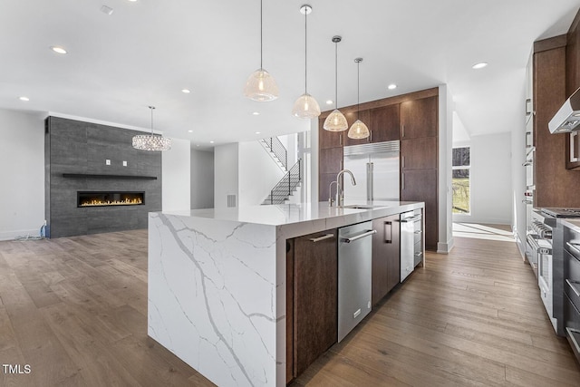 kitchen featuring pendant lighting, sink, high quality appliances, a spacious island, and light stone countertops