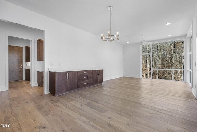 unfurnished room featuring a chandelier and light wood-type flooring