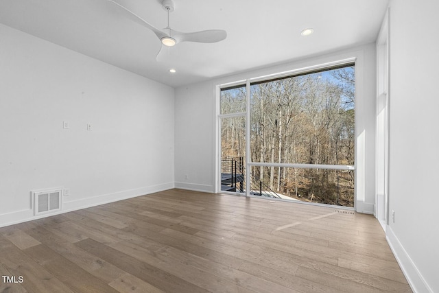 unfurnished room featuring wood-type flooring, expansive windows, and ceiling fan