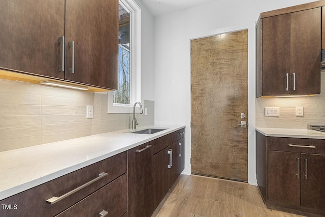 kitchen with tasteful backsplash, light hardwood / wood-style floors, sink, and dark brown cabinets