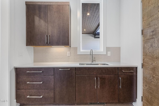 kitchen featuring dark brown cabinetry, sink, and decorative backsplash