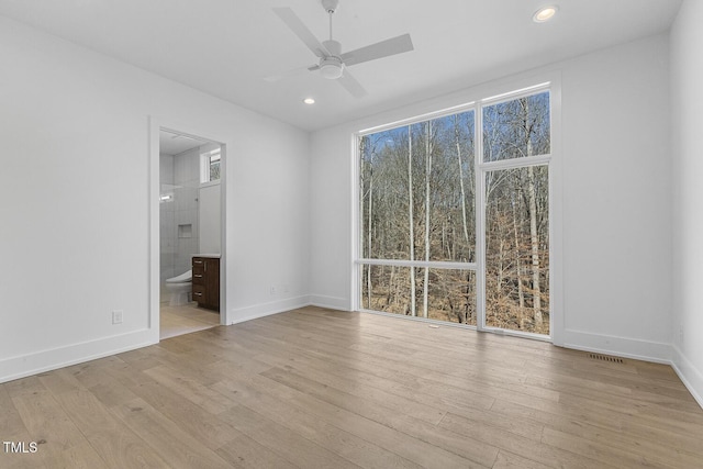 unfurnished bedroom featuring multiple windows, ceiling fan, light wood-type flooring, and ensuite bath