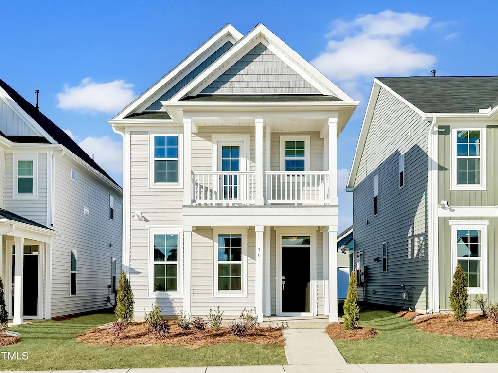 view of front of property featuring a balcony and a front lawn