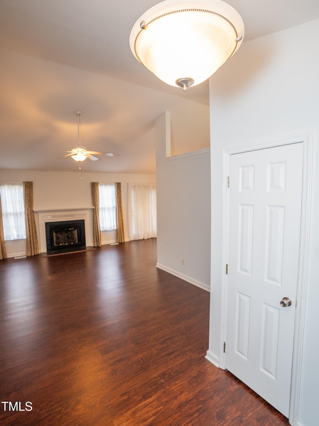 unfurnished living room featuring ceiling fan and dark hardwood / wood-style flooring