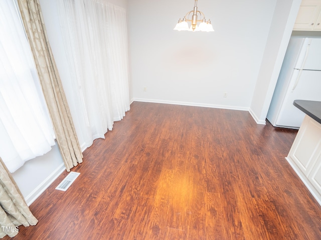 unfurnished dining area with dark hardwood / wood-style flooring and a chandelier