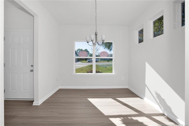 unfurnished dining area featuring a chandelier and dark hardwood / wood-style floors