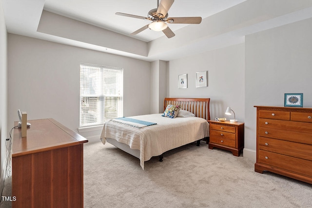 carpeted bedroom with a tray ceiling and ceiling fan