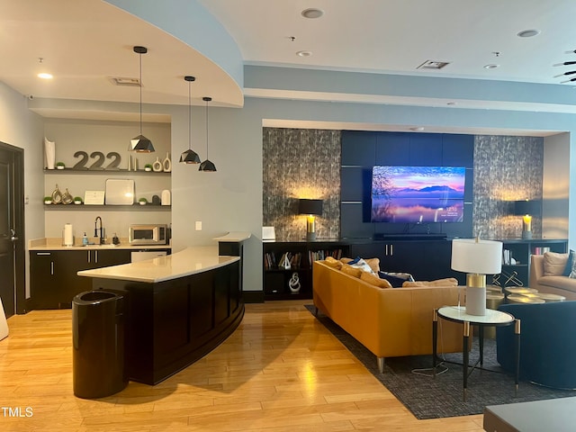 bar with light hardwood / wood-style flooring, hanging light fixtures, and sink