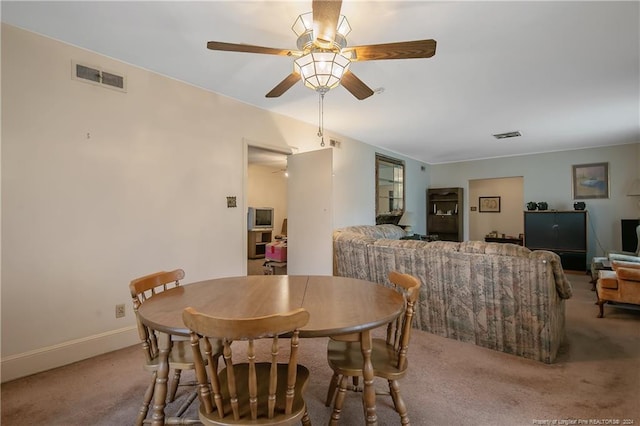 dining space with ceiling fan and light carpet