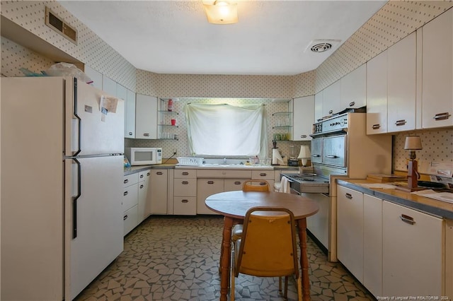 kitchen with white appliances, white cabinetry, and sink