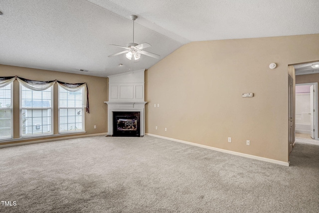 unfurnished living room with a large fireplace, ceiling fan, light colored carpet, and vaulted ceiling