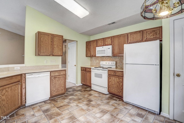 kitchen with tasteful backsplash, a textured ceiling, an inviting chandelier, white appliances, and vaulted ceiling