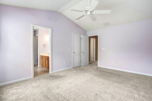 unfurnished bedroom with light colored carpet, lofted ceiling, ceiling fan, and ensuite bath